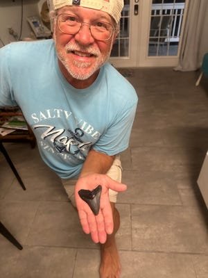Brad Vanderstow holds the large megalodon tooth he found on March 6 on South Englewood Beach near Stump Pass.